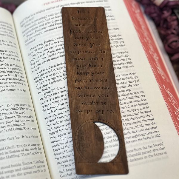 Walnut bookmark engraved with the dangerous business quote, resting in an open book
